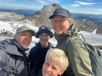 Betina, manden Morten og deres to børn foran snedækkede bjerge.