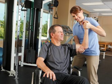 Fysioterapeut hjælper mand i kørestol.