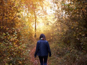 Kvinde set fra ryggen går i efterårsskov