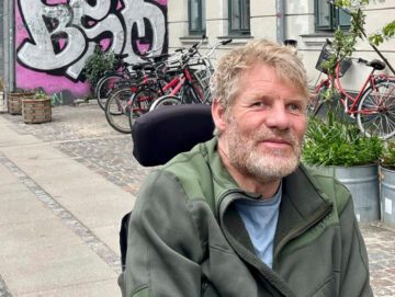 Anders Thordal sidder i sin kørestol med graffiti i baggrunden.
