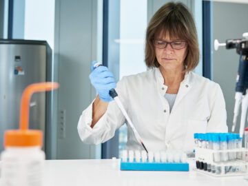 Kvinde står i laboratorium med pipette i hånden.