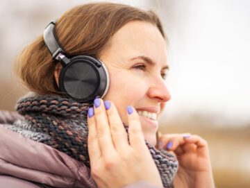 Kvinde i vintertøj smiler, mens hun har hørebøffer på