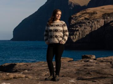 Anna Katrin står med smuk færøsk natur i baggrunden.