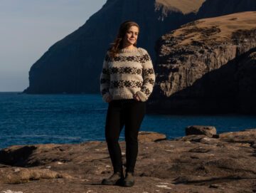 Anna Katrin står med smuk færøsk natur i baggrunden.