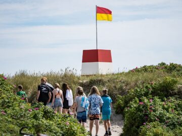 En gruppe af børn på vej på stranden med livreddertårnet i baggrunden