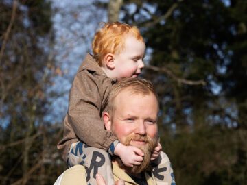 Chris går ude i naturen med sin søn siddende på skuldrene.