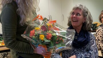 Kvinde der smiler og modtager blomster