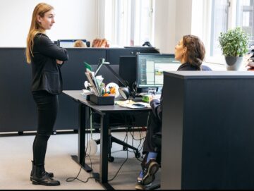 To kolleger der konverserer ved skrivebordet