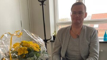 Mand der sidder med en bukket blomster ved siden af sig