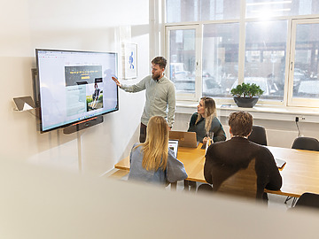 Mennesker i et mødelokale, der får vist en præsentation