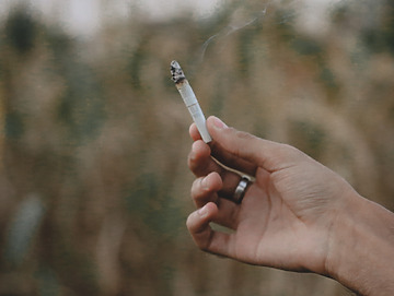 Hånd holder en tændt cigaret