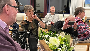 Mand der sidder med en buket blomster, mens en anden mand fotograferer det