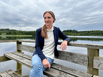 Kvinde der sidder på en bænk ved vandet