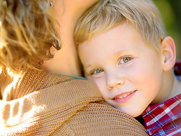 En lille dreng omfavnes af sin mor