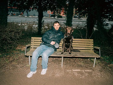 Oliver sidder på en bænk med sin hund